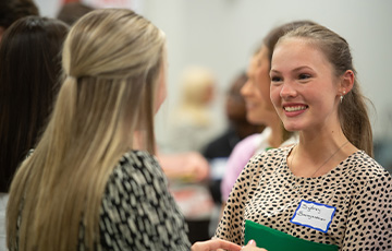 A female student (right) speaking to a female employer (left).