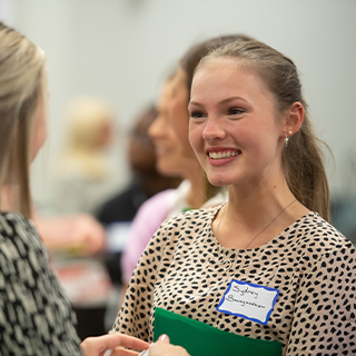 Two female participants during a job fair, one is in focus.