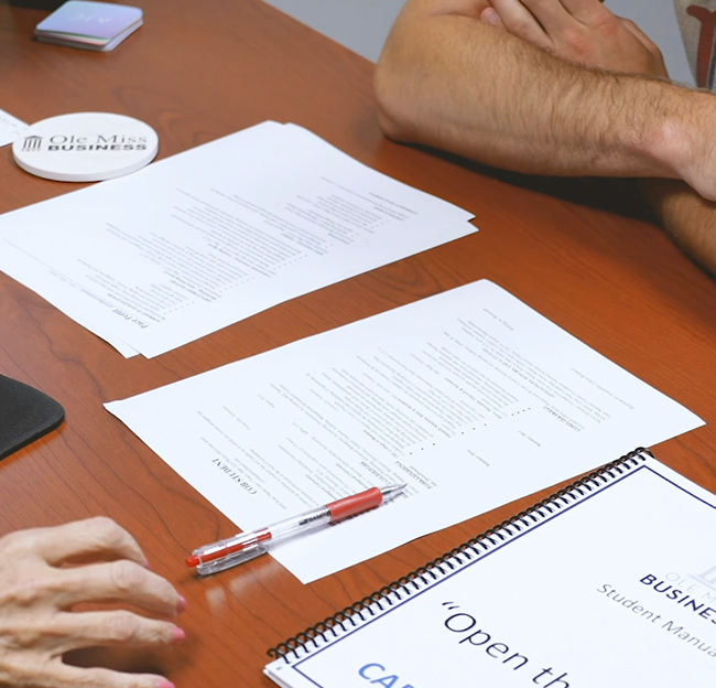 A close up image of forms laid out on a table with a person's arms crossed.