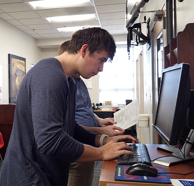 A student picking his courses on a desktop computer located at the advising office inside the business school.