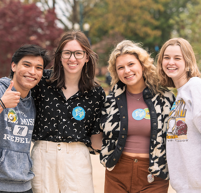 A photo of four students smiling for the camera.