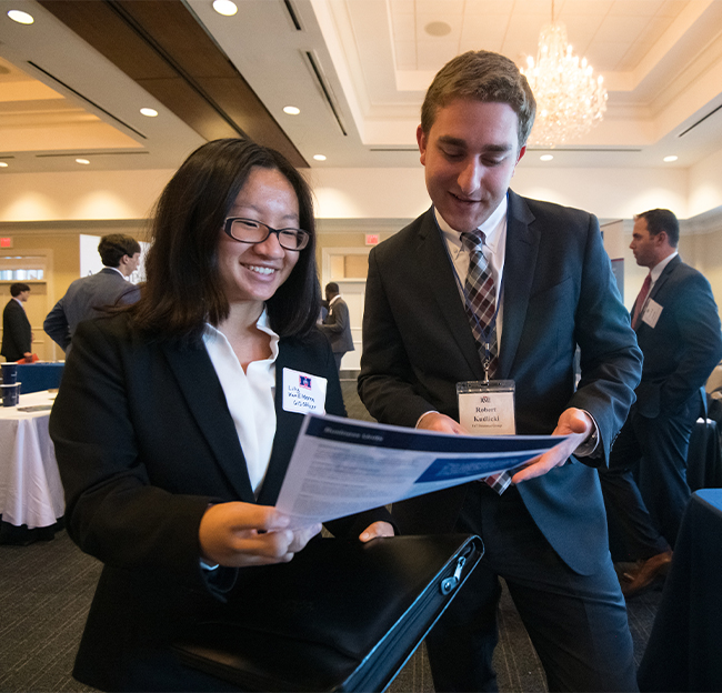 A female and male participant during a job fair looking over a piece of paper.