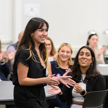 Classmates cheering another classmate during the Serving the South Business Model Competition in 2022.