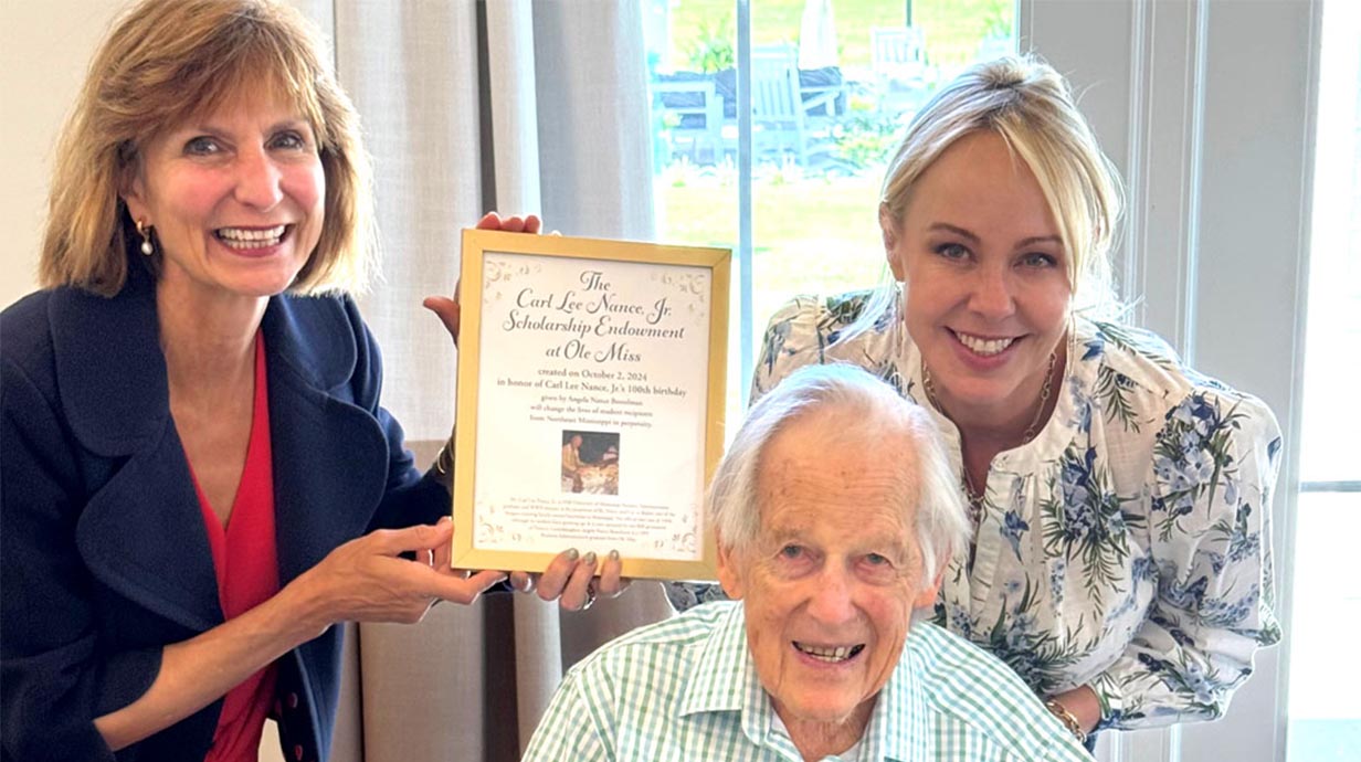 Vice Chancellor for Development Charlotte Parks (left) and Angela Nance Bostelman (right) present a framed endowment certificate to Carl Lee Nance Jr. in honor of his 100th birthday. 