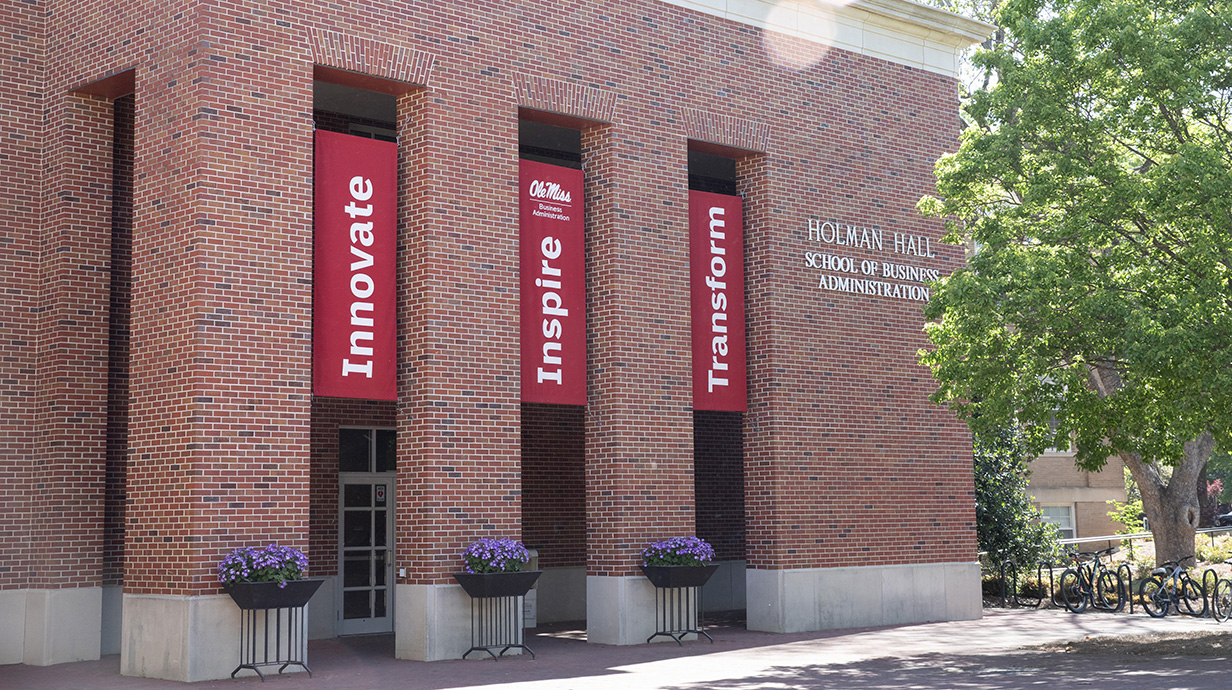 A red brick building is decorated with large red banners reading 'Innovate,' 'Inspire' and 'Transform.'