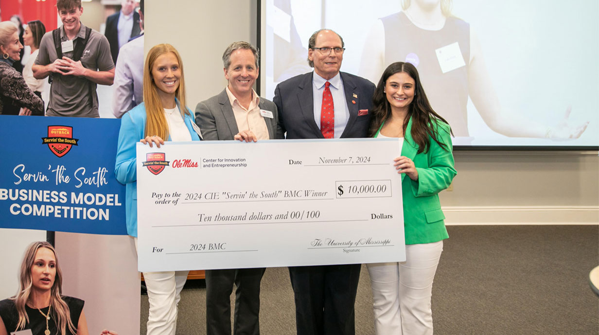 Photo of two students (first and fourth), Rich Gentry (second), and Steve Grantham, third from left, helps judge the annual “Servin’ the South” Collegiate Business Model Competition at Ole Miss and is a member of the CIE board of directors. Photo by UM MarComm