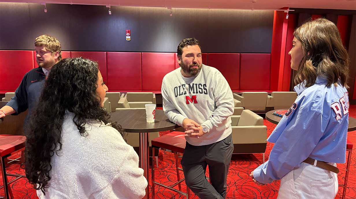 Photo of Suezette Salazar and a fellow female student speaking with an athletic employee. 