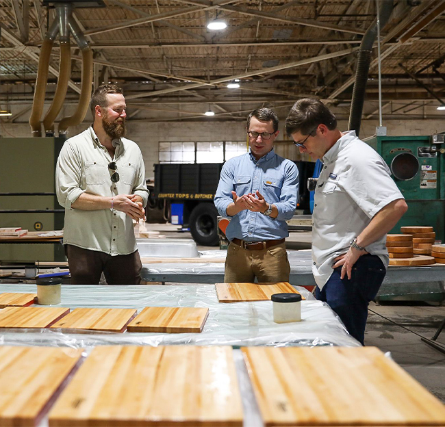 Ben Napier with two others in a warehouse looking over Scotsman cutting boards.