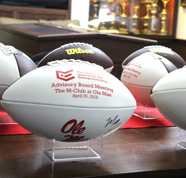 Image of signed footballs and wording stating the CIE Advisory Board Meeting