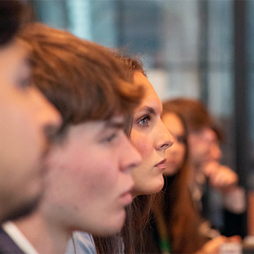 A row of students with one face in focus during a presentation at Microsoft ATL during the Career Trek.