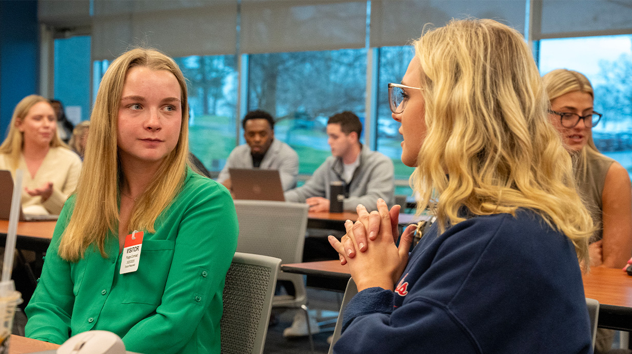 Photo of Paige Conrad (left) speaking to a Dell employee (right).