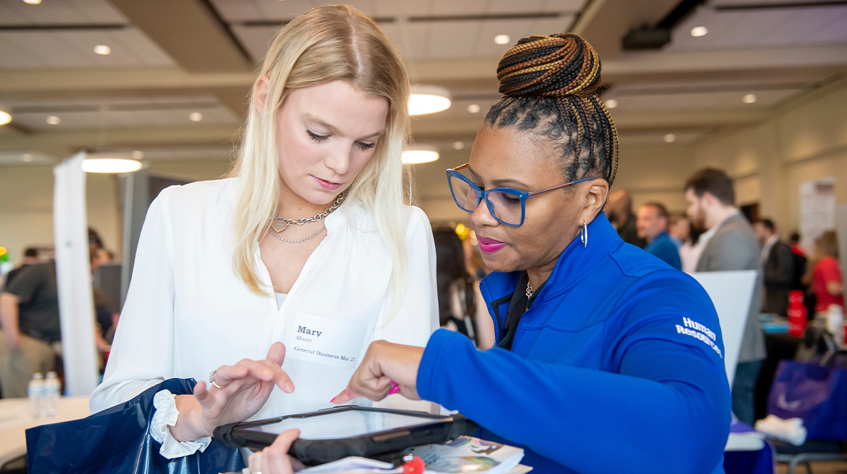 A student and an HR employer looking at an iPad during an internship fair.